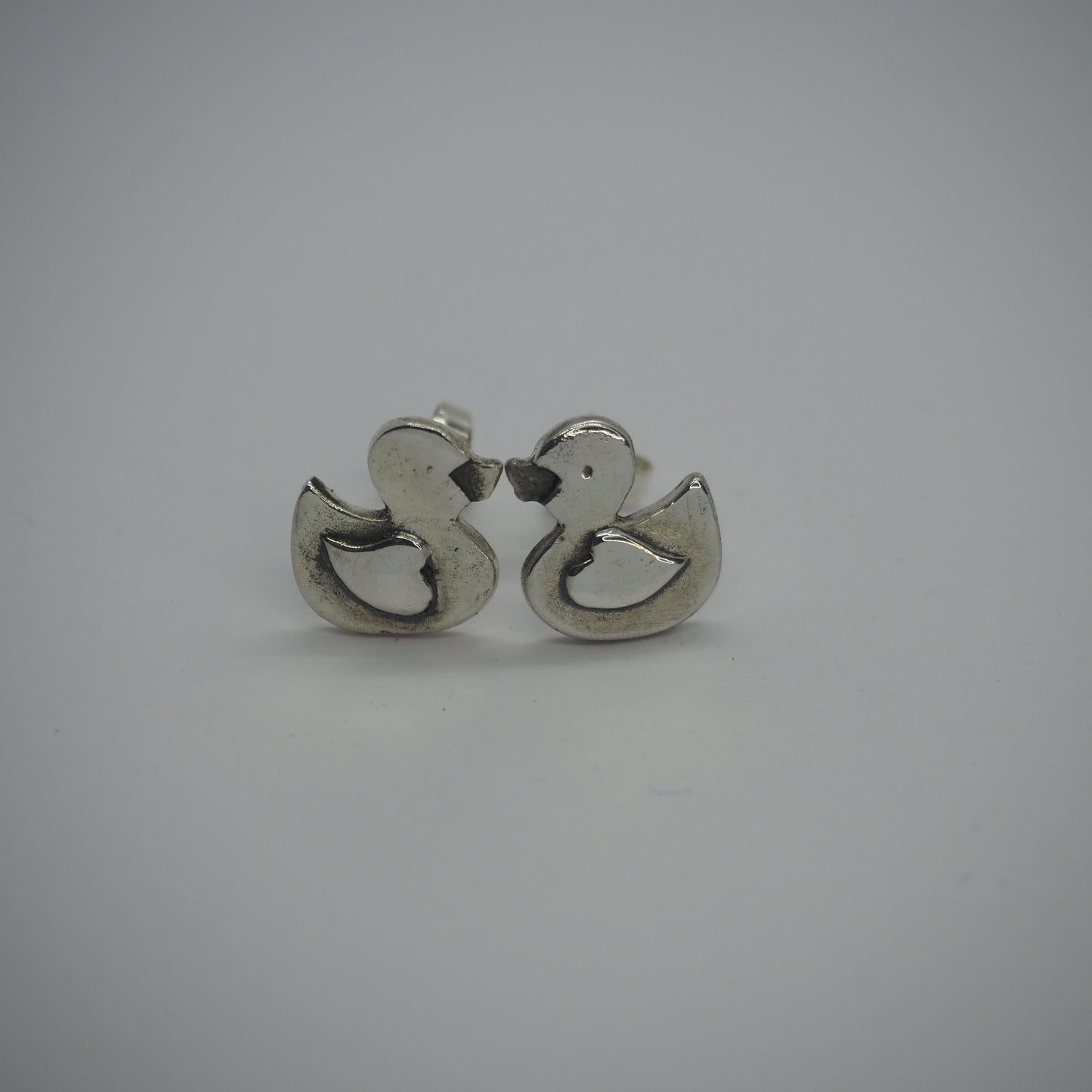 A pair of adorable tiny rubber duck stud earrings handmade in fine silver set on sterling silver posts.