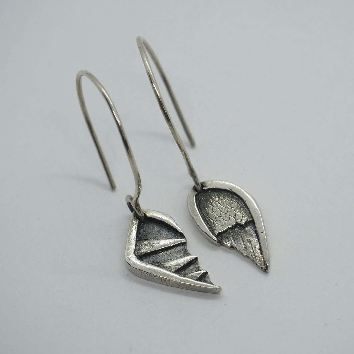 A delightful pair of fine silver angel and devil wing earrings hung on handmade sterling silver loops.
