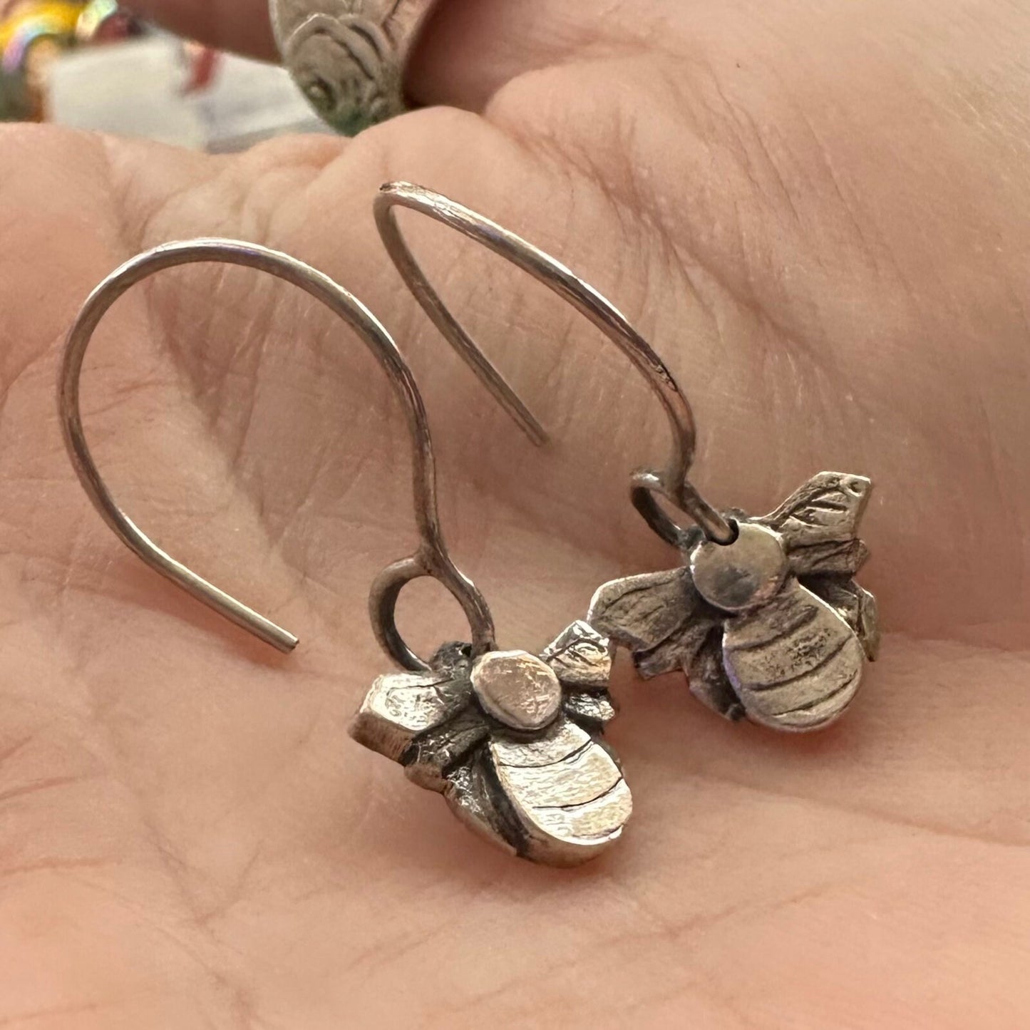 A stunning little pair of handmade fine silver bee earrings hung on hand formed sterling silver wires.