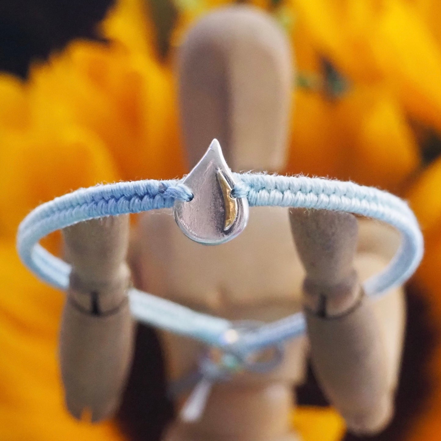 A gorgeous simple fine silver raindrop with gold highlights on a lovely blue leather, cotton and sterling silver friendship bracelet.
