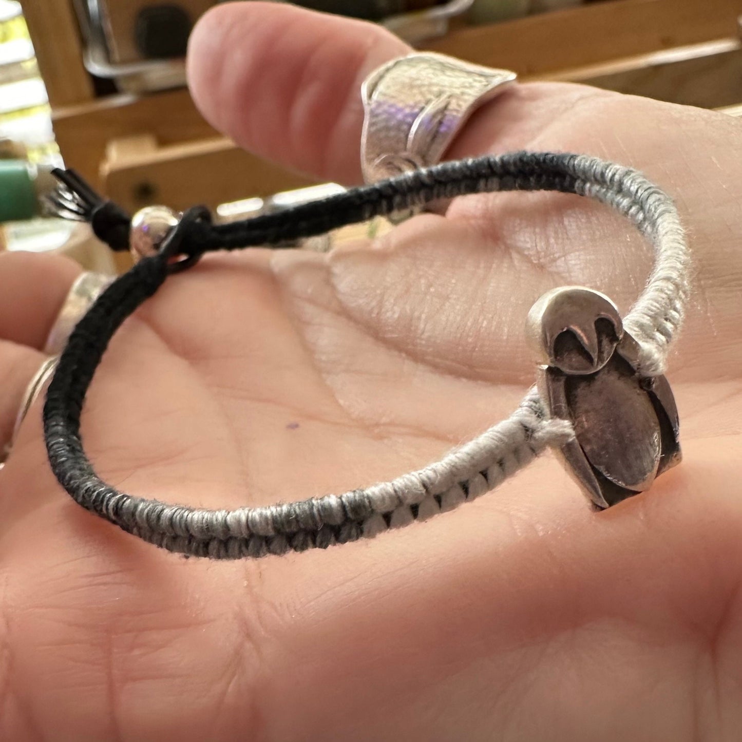 A cute tiny fine silver penguin on a beautiful black and white leather, sterling silver and cotton friendship bracelet.