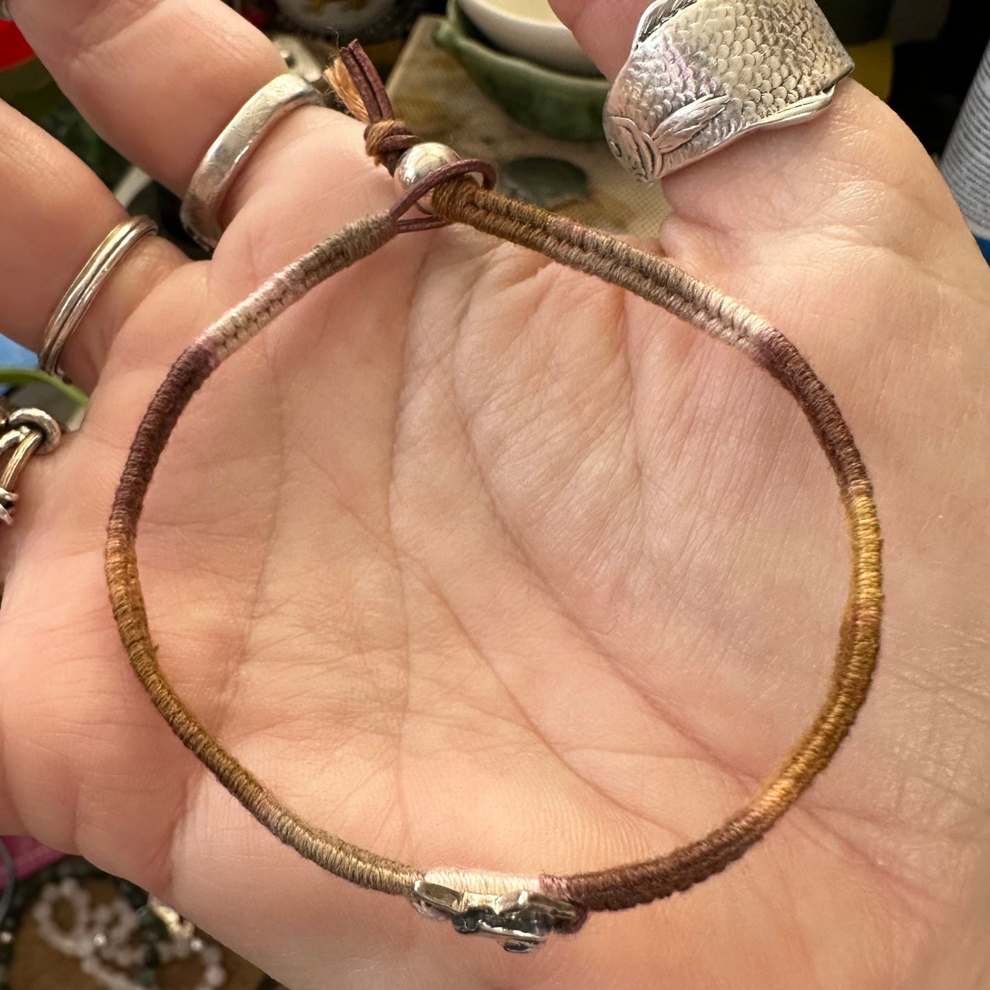 A gorgeous handmade fine silver wolf face on a shades of brown leather, cotton and sterling silver  woven charm bracelet.