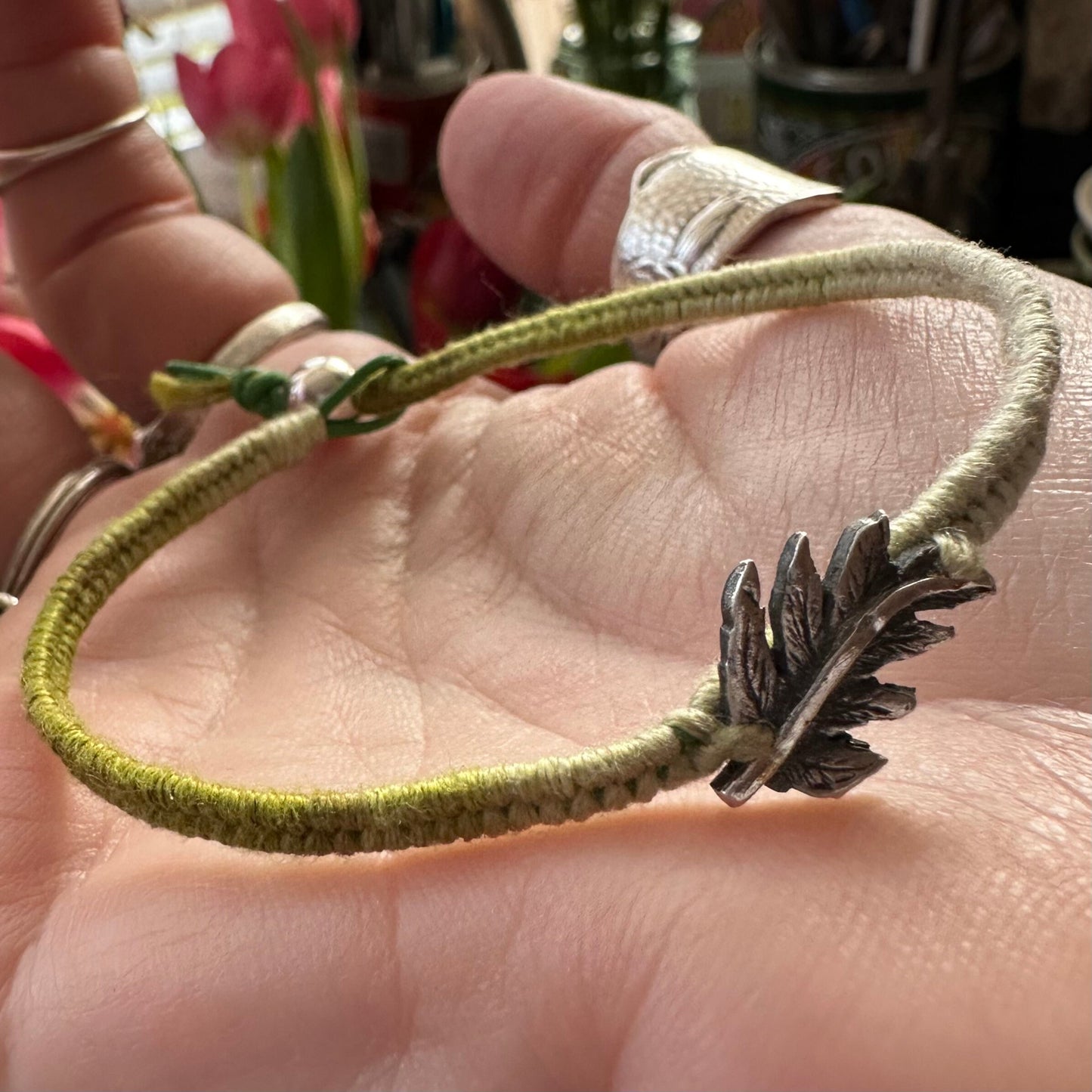 A beautiful green leather and cotton friendship bracelet with a lovely fine silver fern leaf.