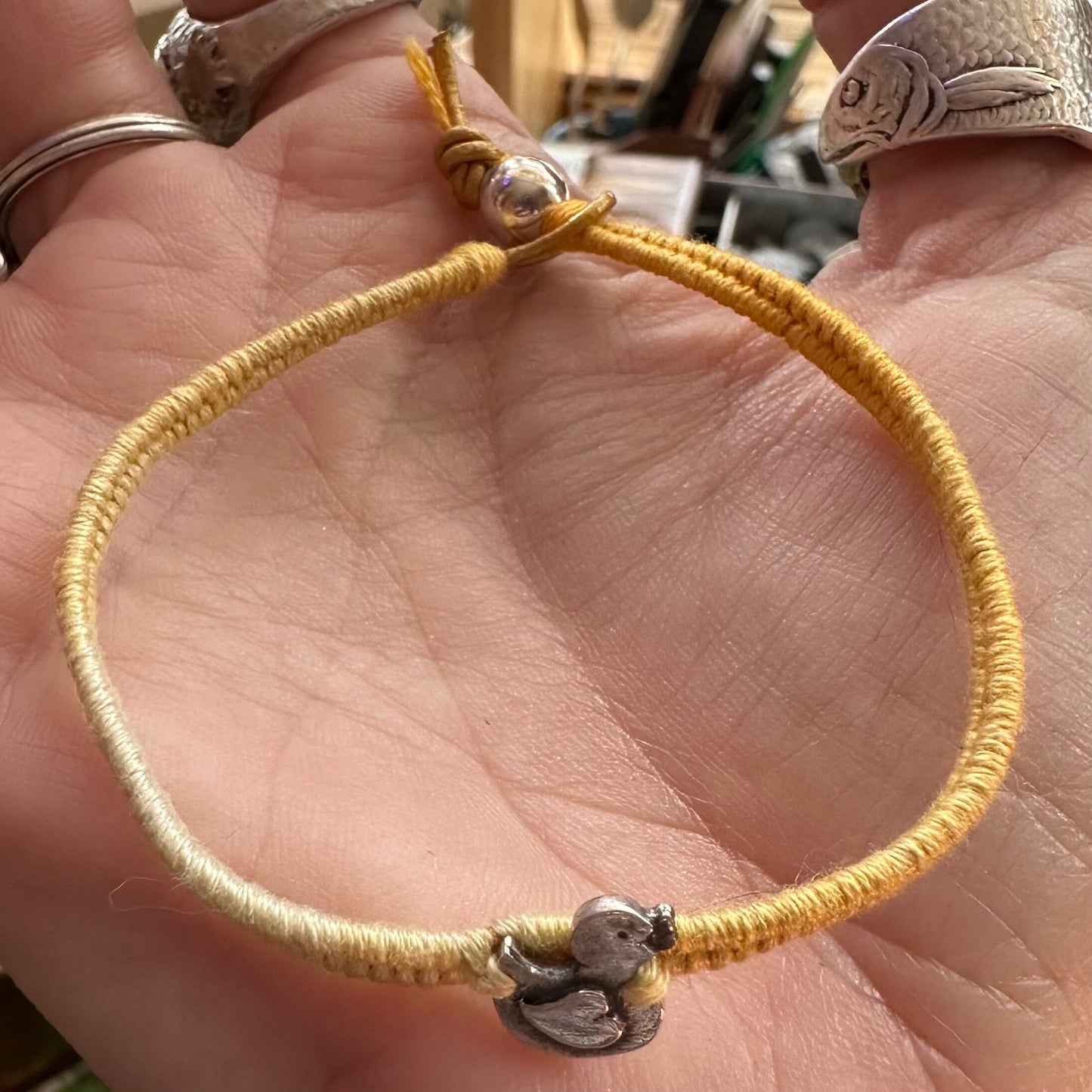 A mini duckling handmade in fine silver on a gorgeous yellow friendship bracelet in leather, cotton and sterling silver.