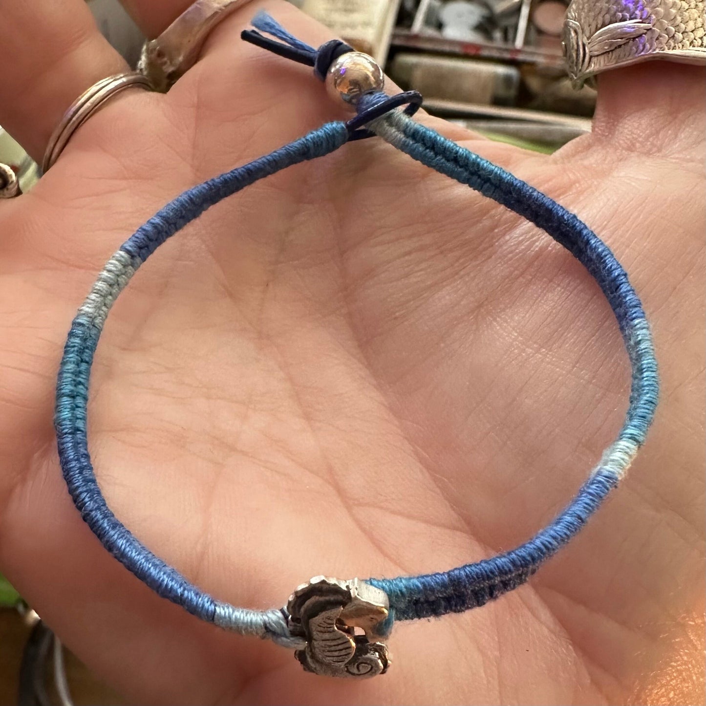A beautiful hand made fine silver seahorse on a gorgeous graduated blue cotton, leather and sterling silver friendship bracelet.