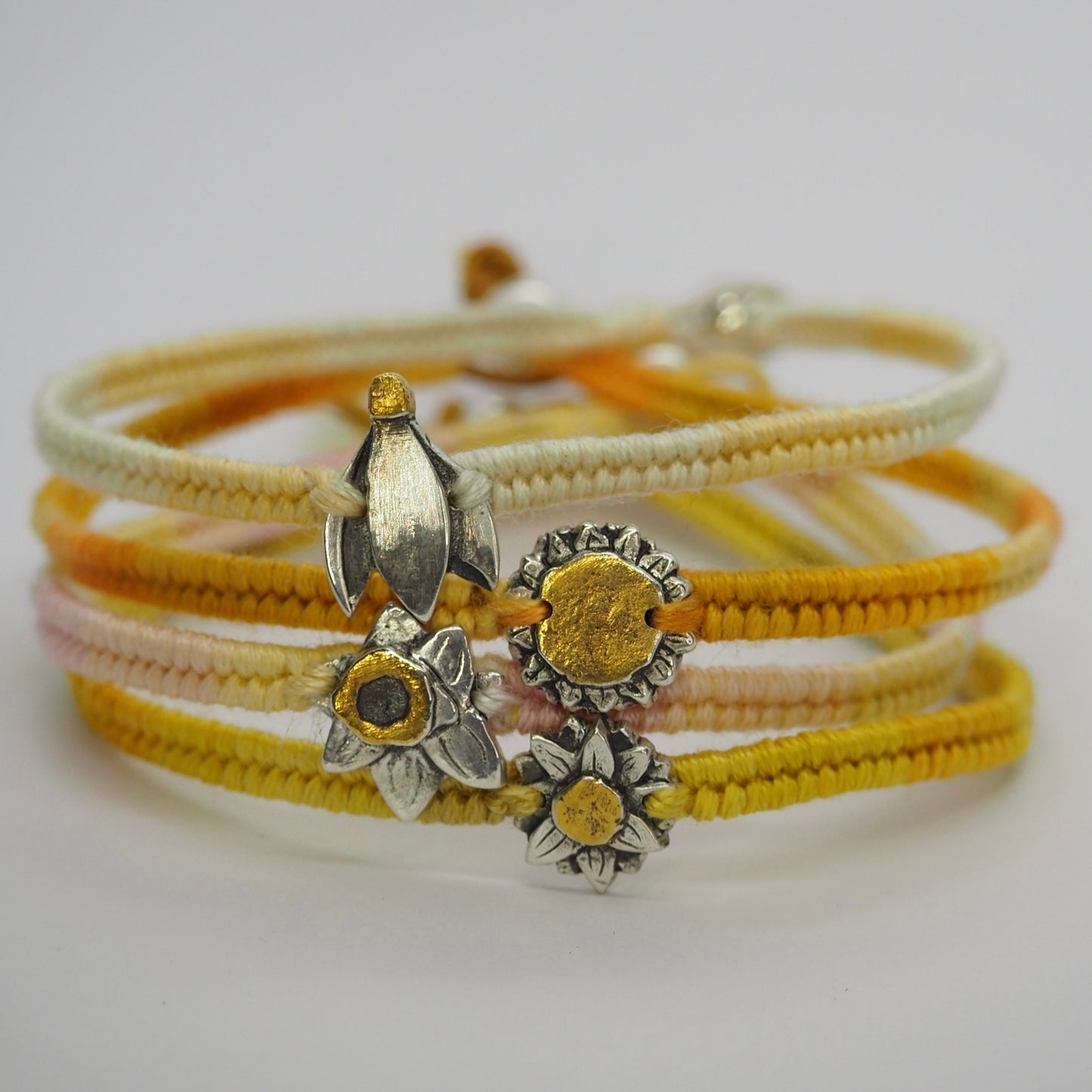 A 24k gold centred sunflower handmade in fine silver on a gorgeous yellowy orange woven leather, cotton and sterling silver charm bracelet.