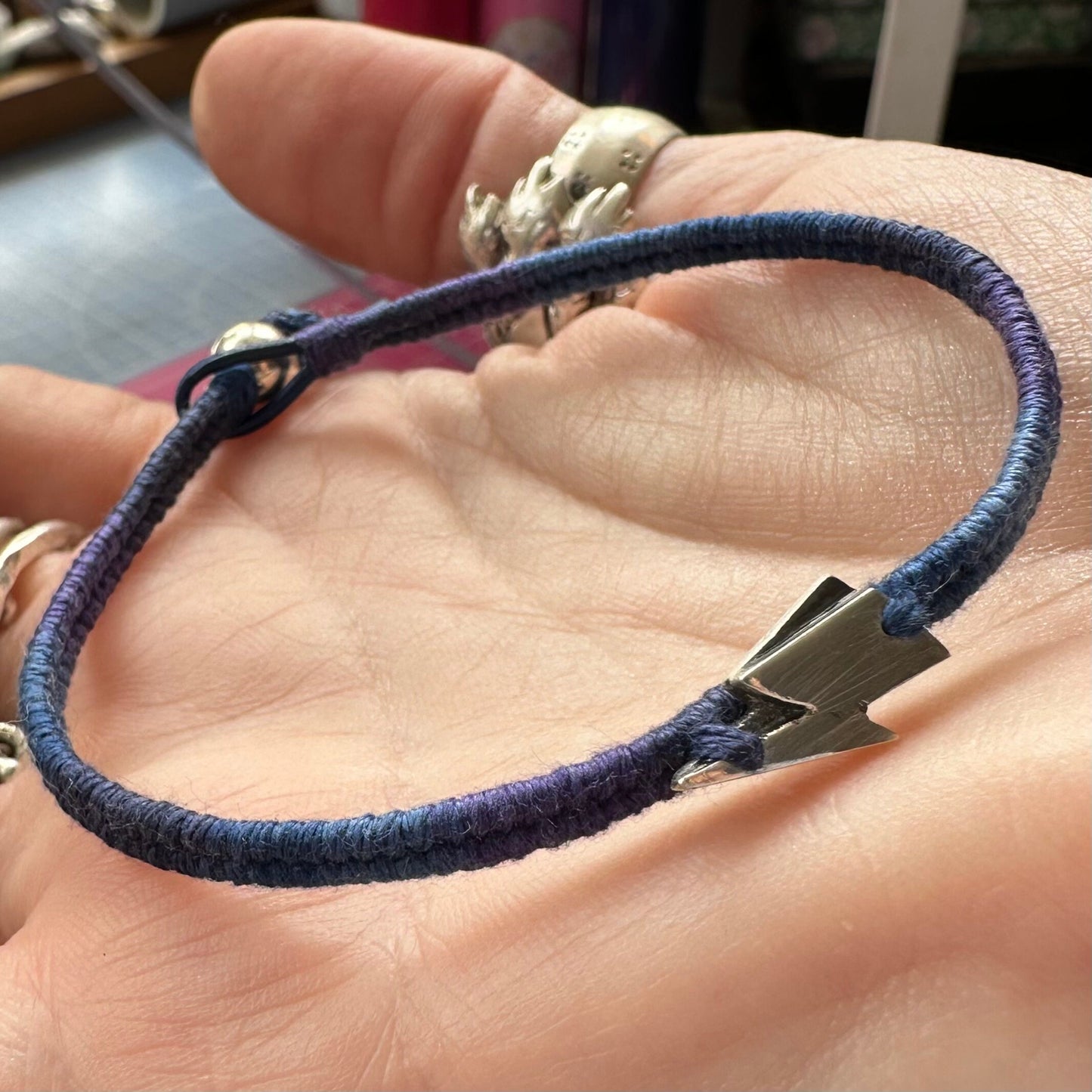 A beautiful hand made fine silver lightning bolt on a gorgeous graduated blue cotton, leather and sterling silver friendship bracelet.