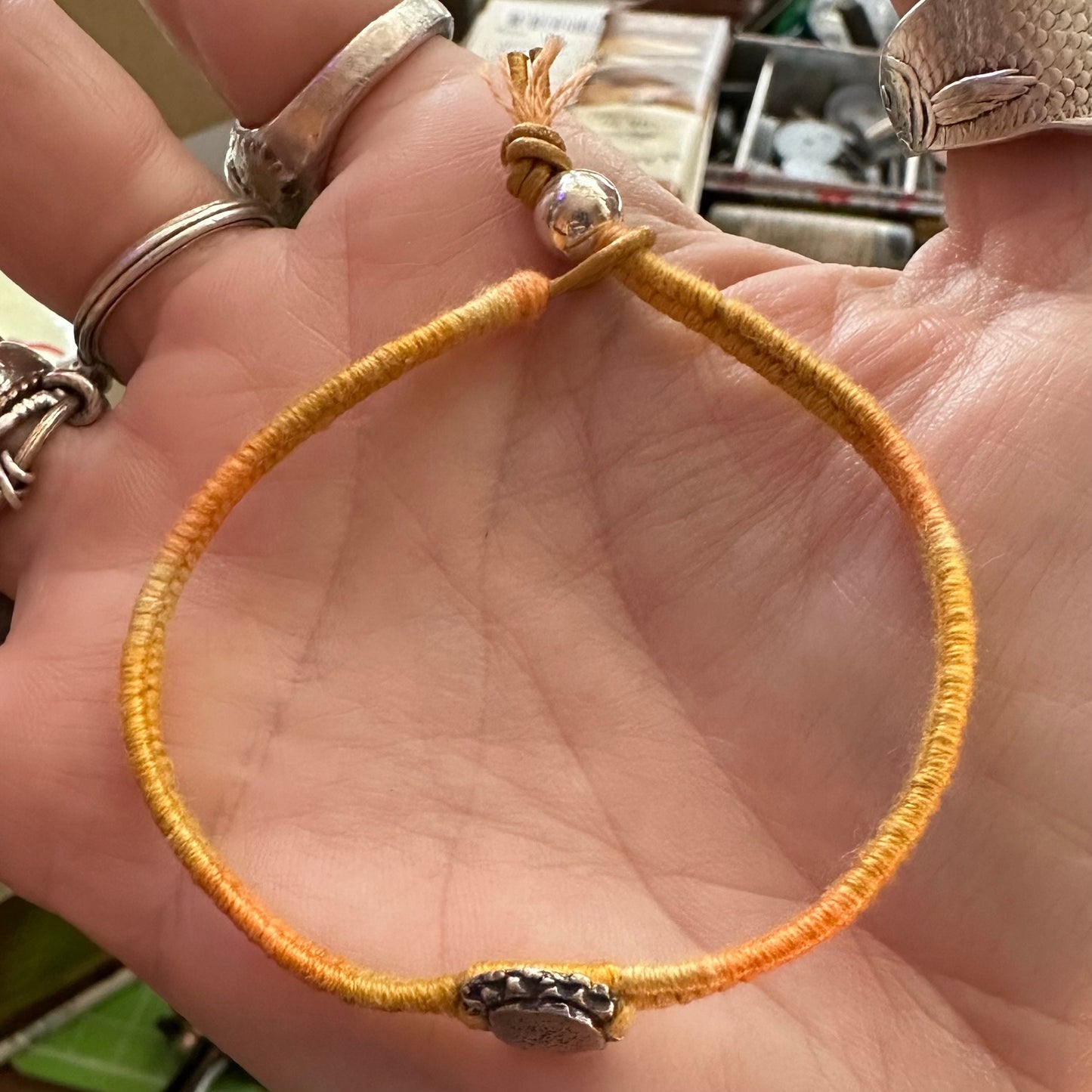 A gorgeous sunflower handmade in fine silver on a gorgeous yellowy orange woven leather, cotton and sterling silver charm bracelet.