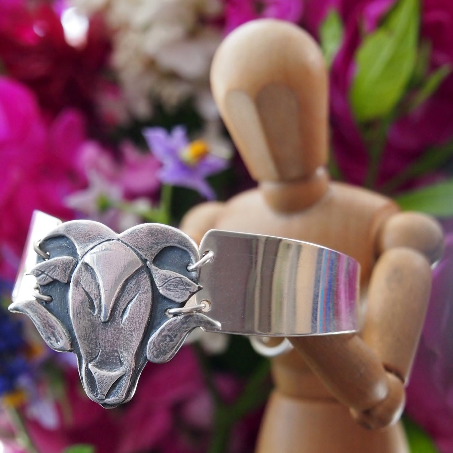 A chunky hand made fine silver rams head on a wide sterling silver bangle.