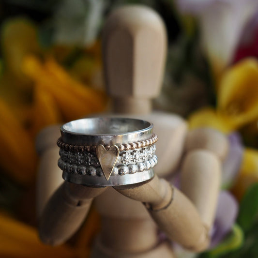 A pretty handmade sterling silver ring with separate handcut 9ct gold heart on flower band, silver and gold filled spinner ring.