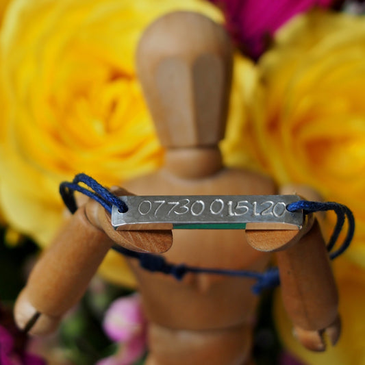 A custom children's security bracelet , hand stamped on chunky sterling silver on waxed cotton.