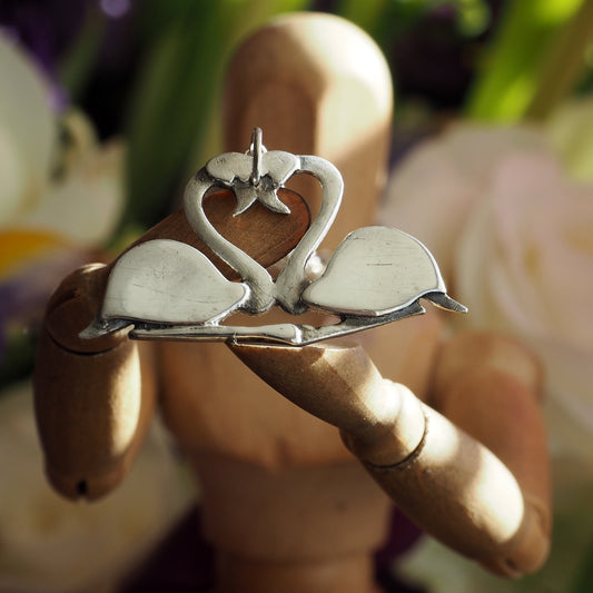 A pair of beautifully simple sitting fine silver flamingos pendant, handmade and hung on a sterling silver chain.