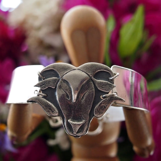 A chunky hand made fine silver rams head on a wide sterling silver bangle.