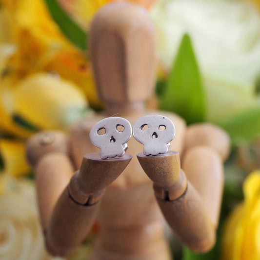 A tiny pair of simple little fine silver skull stud earrings on sterling silver posts.