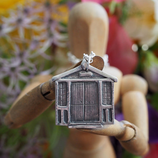 An adorable little eco friendly fine silver double fronted beach hut pendant hung on a sterling silver chain.