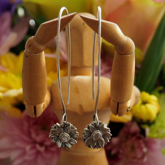 A beautiful pair of sunflower earrings handmade in fine silver and hung on long sterling silver wires.