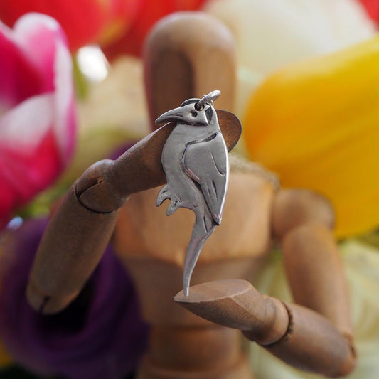 A lovely mynah bird pendant handmade in fine silver hung on a sterling silver chain .