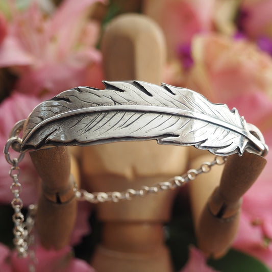 A stunning handmade fine silver feather backed with hand cut sterling silver on a sterling silver chain bracelet.