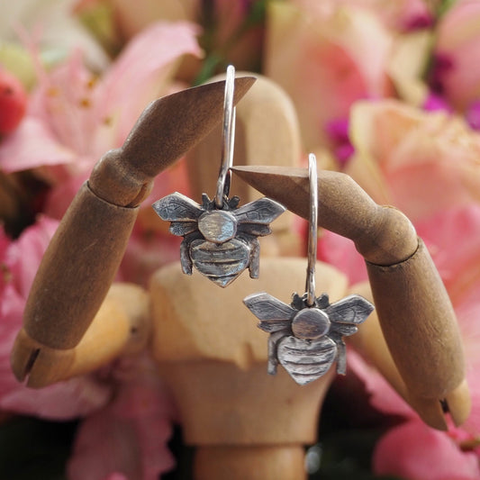 A stunning simple pair of handmade fine silver bee earrings hung on hand formed sterling silver wires.