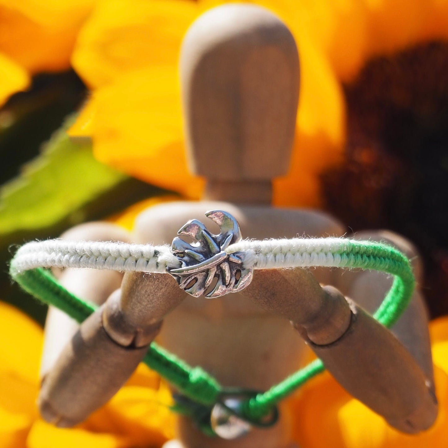 A gorgeous vivid green and white friendship bracelet in leather, cotton and sterling silver with a handmade fine silver monstera leaf.