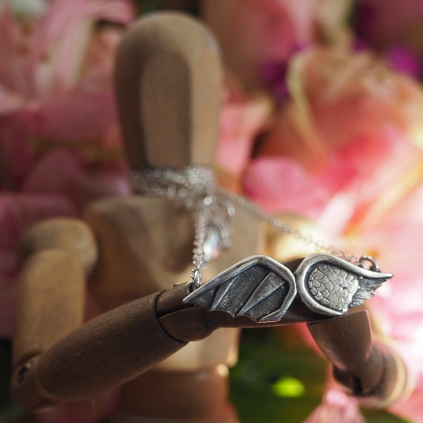 A gorgeous handmade fine silver Angel and Devil Wings necklace hung on a sterling silver chain.