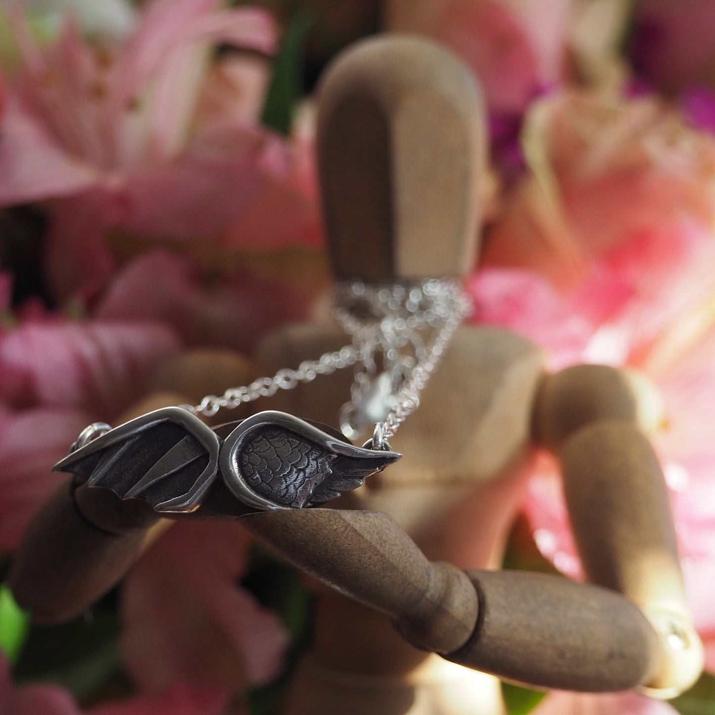 A gorgeous handmade fine silver Angel and Devil Wings necklace hung on a sterling silver chain.