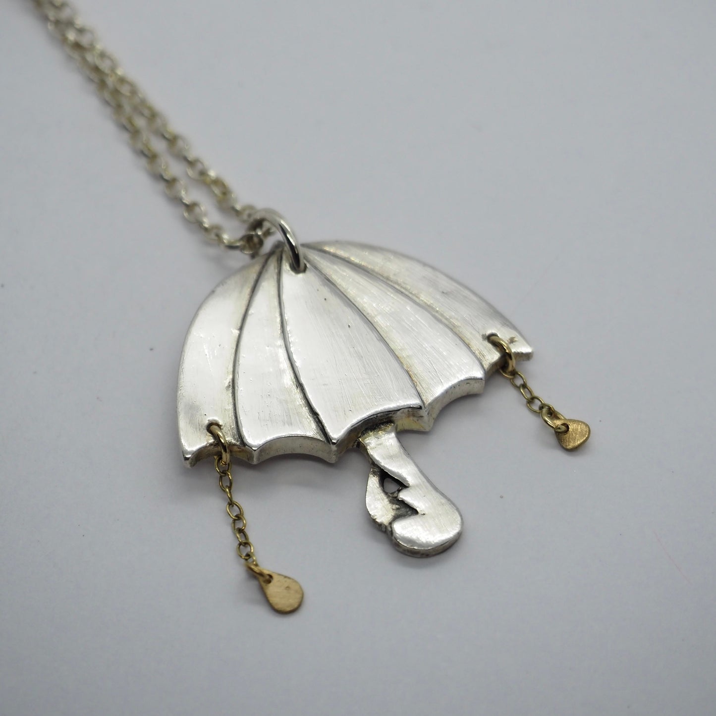 A beautiful unique fine silver flamingo umbrella necklace with tiny gold rain drops.