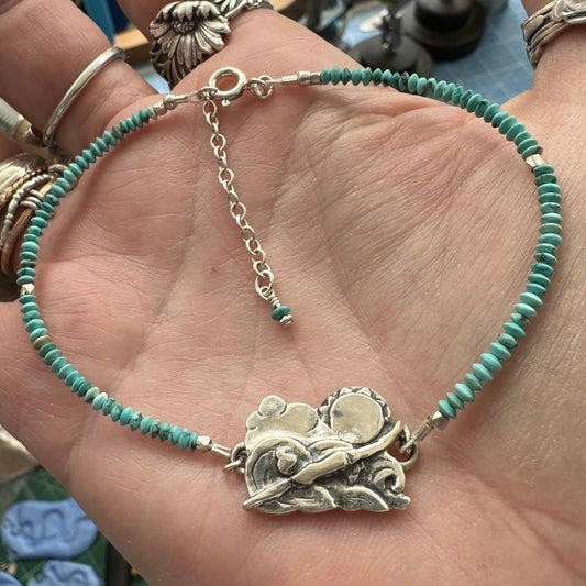 A beautiful handmade fine silver cold water sea swimmer charm strung on a bracelet of tiny turquoise and sterling silver beads.