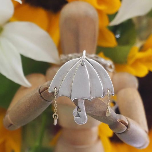 A beautiful unique fine silver flamingo umbrella necklace with tiny gold rain drops.