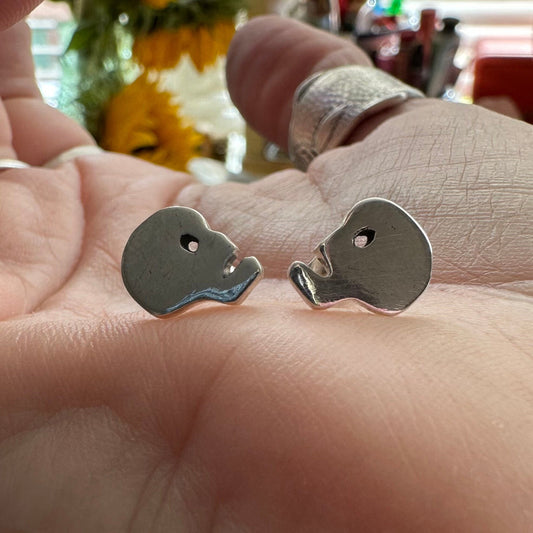 A pair of tiny little fine silver skull stud earrings on sterling silver posts.