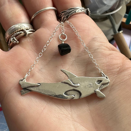 A beautiful little orca killer whale handmade in fine silver pendant on a sterling silver chain.