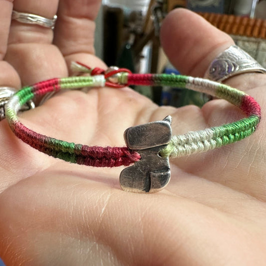 A cute handmade fine silver Christmas Stocking on a festive multi toned leather, cotton and sterling silver woven bracelet.