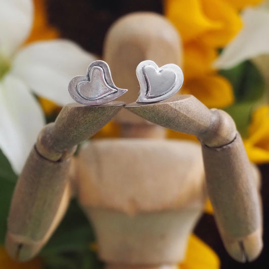 A lovely simple pair of curly heart stud earrings handmade in fine silver set on sterling silver posts.