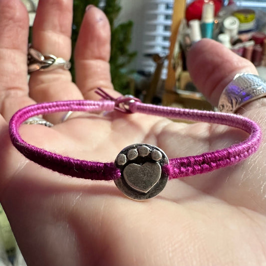 An adorable handmade fine silver heart paw print on a beautiful soft pink leather and cotton friendship bracelet.