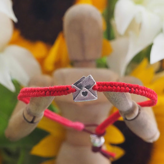 A lovely fine silver love letter hand made in fine silver on a beautiful red leather and cotton friendship bracelet.