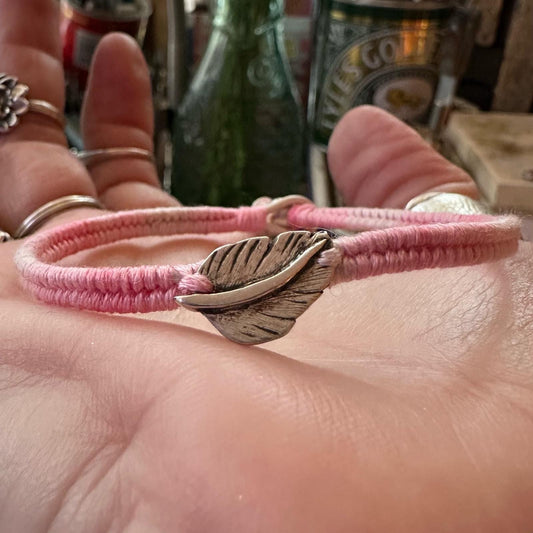 A delightful handmade fine silver feather on a shades of dusty pink friendship bracelet in leather, sterling silver and cotton.