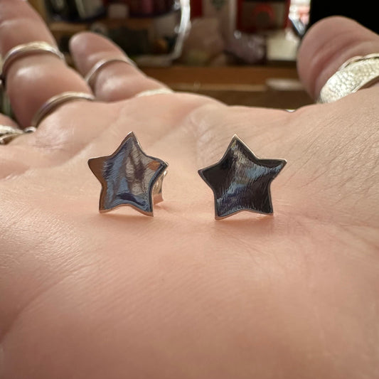 A pair of dainty fine silver star stud earrings on sterling silver posts.