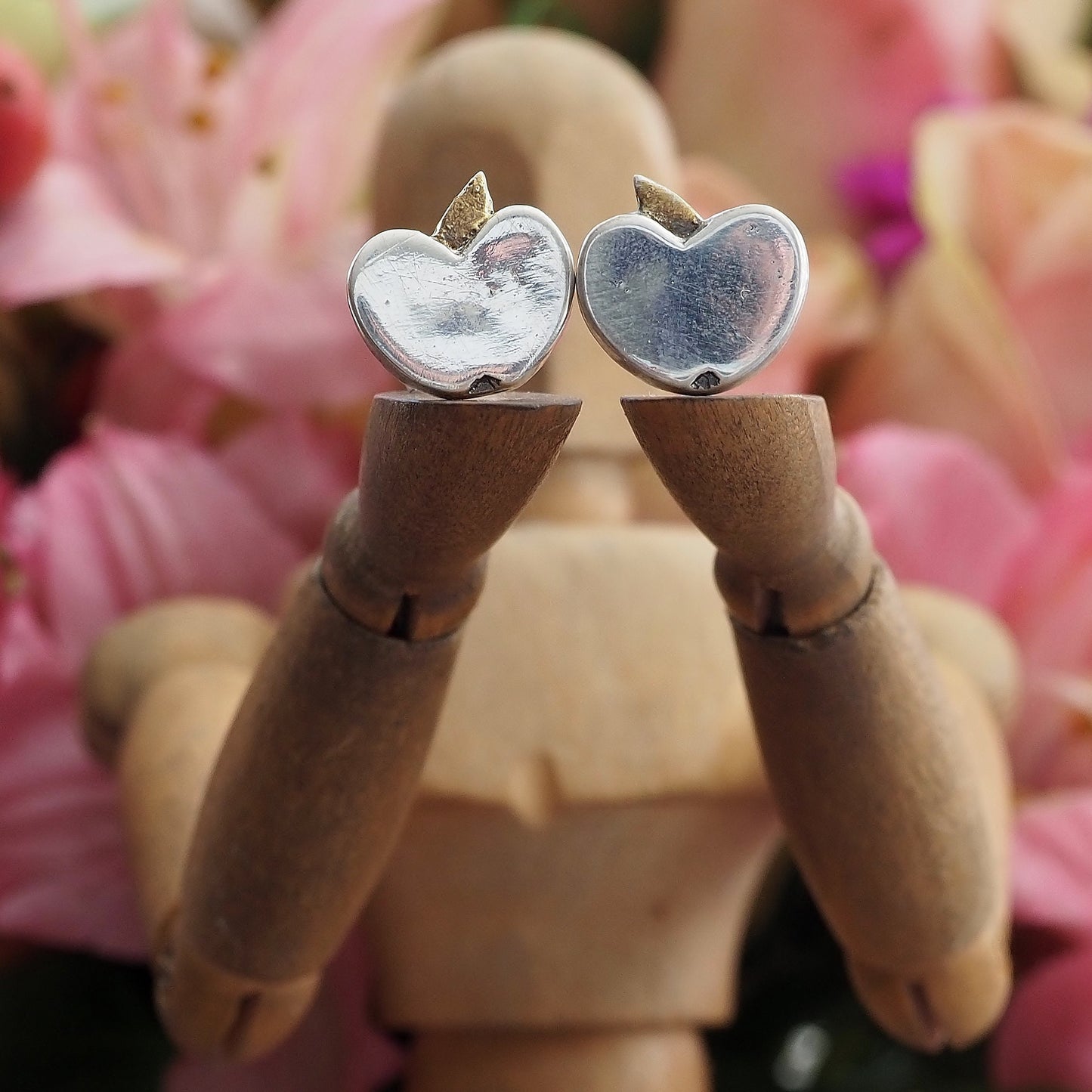 A pair of tiny fine silver apple stud earrings on sterling silver posts enhanced with little gold leaves.