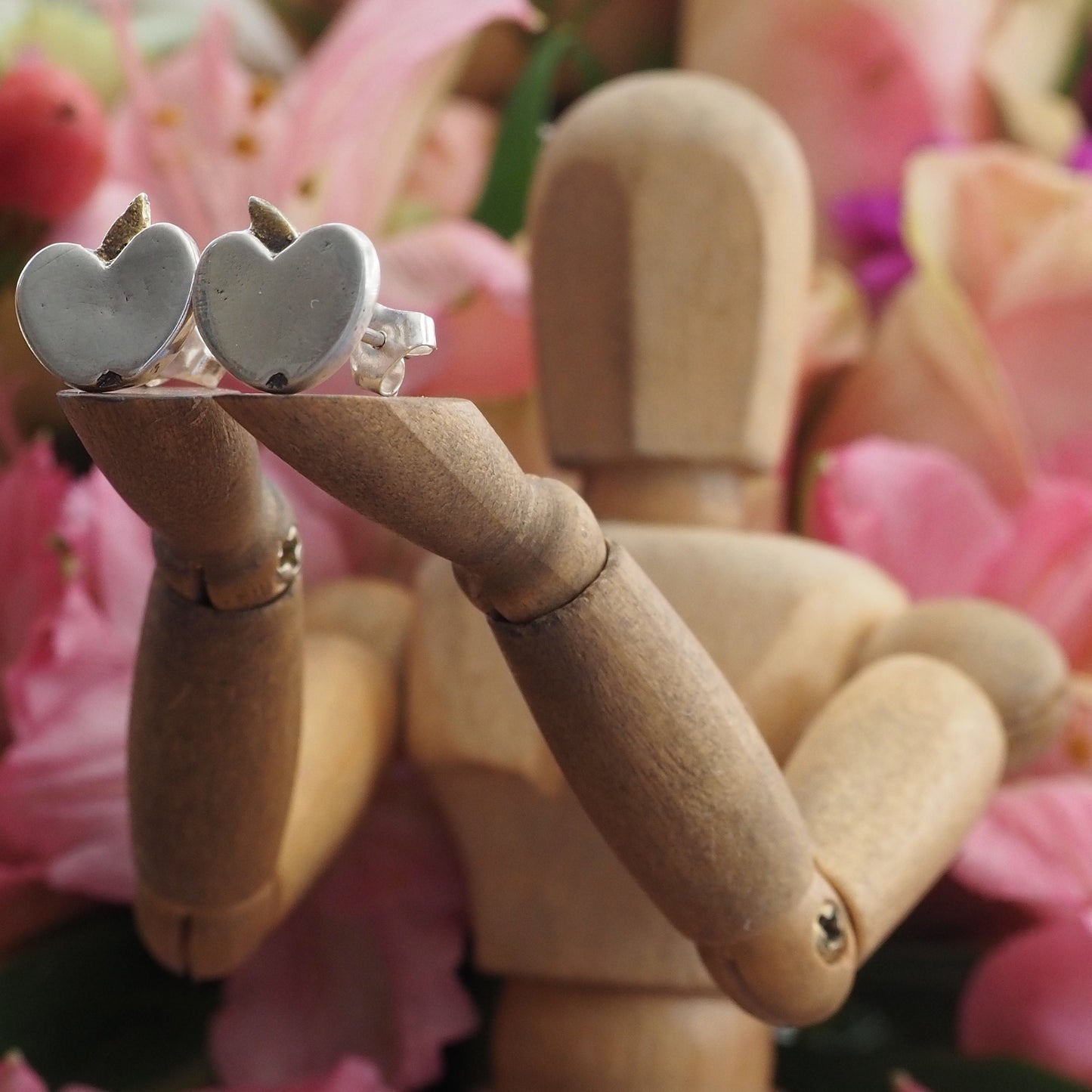 A pair of tiny fine silver apple stud earrings on sterling silver posts enhanced with little gold leaves.