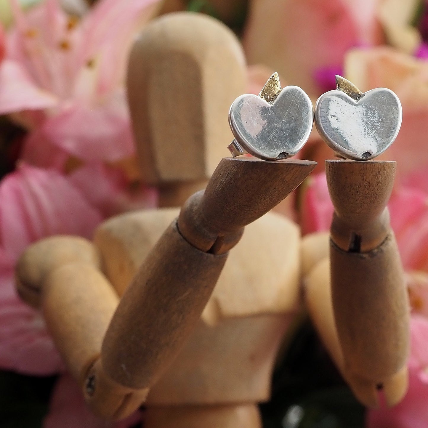 A pair of tiny fine silver apple stud earrings on sterling silver posts enhanced with little gold leaves.