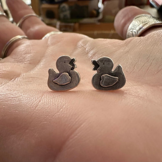 A pair of adorable little rubber duck stud earrings handmade in fine silver set on sterling silver posts.