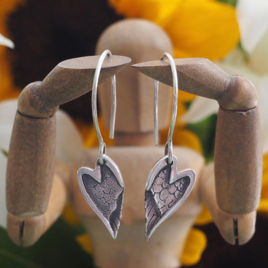 A lovely pair of handmade fine silver angel wing earrings hung on hand formed sterling silver loops.