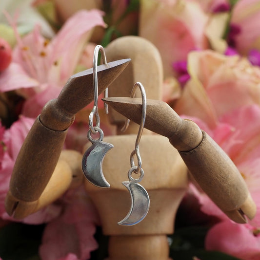 A simple handmade pair of eco friendly fine silver little crescent moon earrings on long sterling silver wires