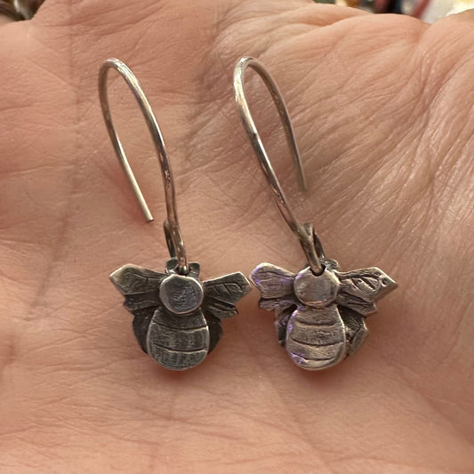 A stunning little pair of handmade fine silver bee earrings hung on hand formed sterling silver wires.