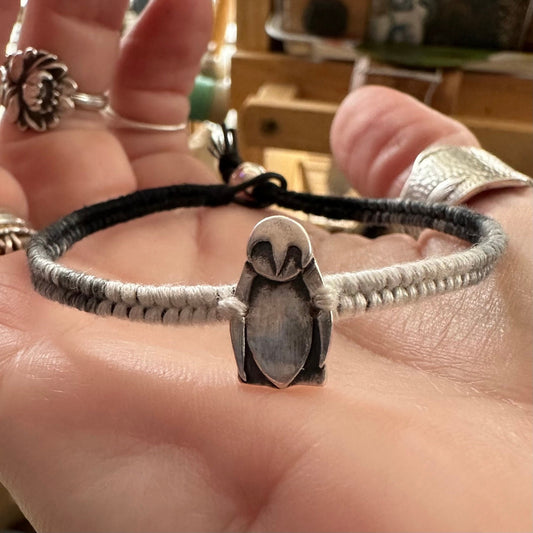 A cute tiny fine silver penguin on a beautiful black and white leather, sterling silver and cotton friendship bracelet.