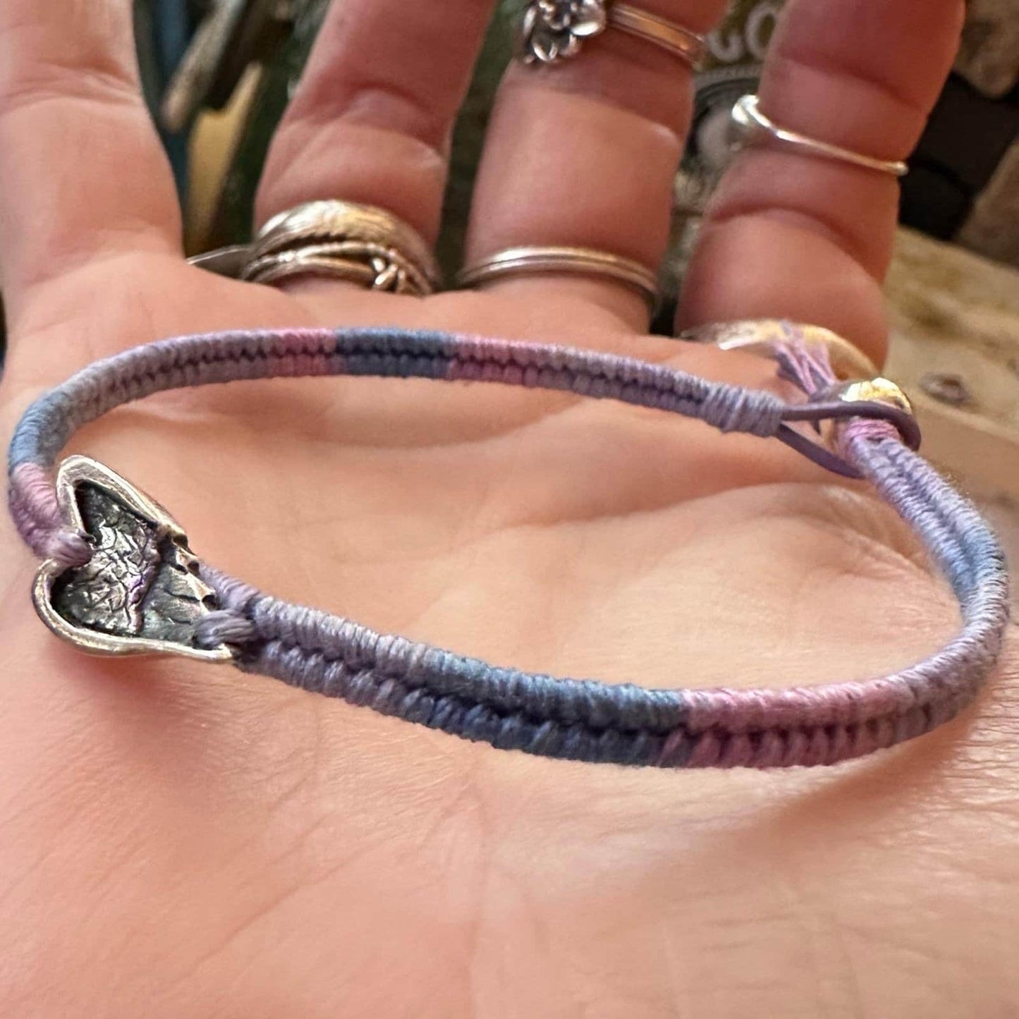 A beautiful little fine silver angel wing on a beautiful pinky purple leather, cotton and sterling silver woven charm bracelet.