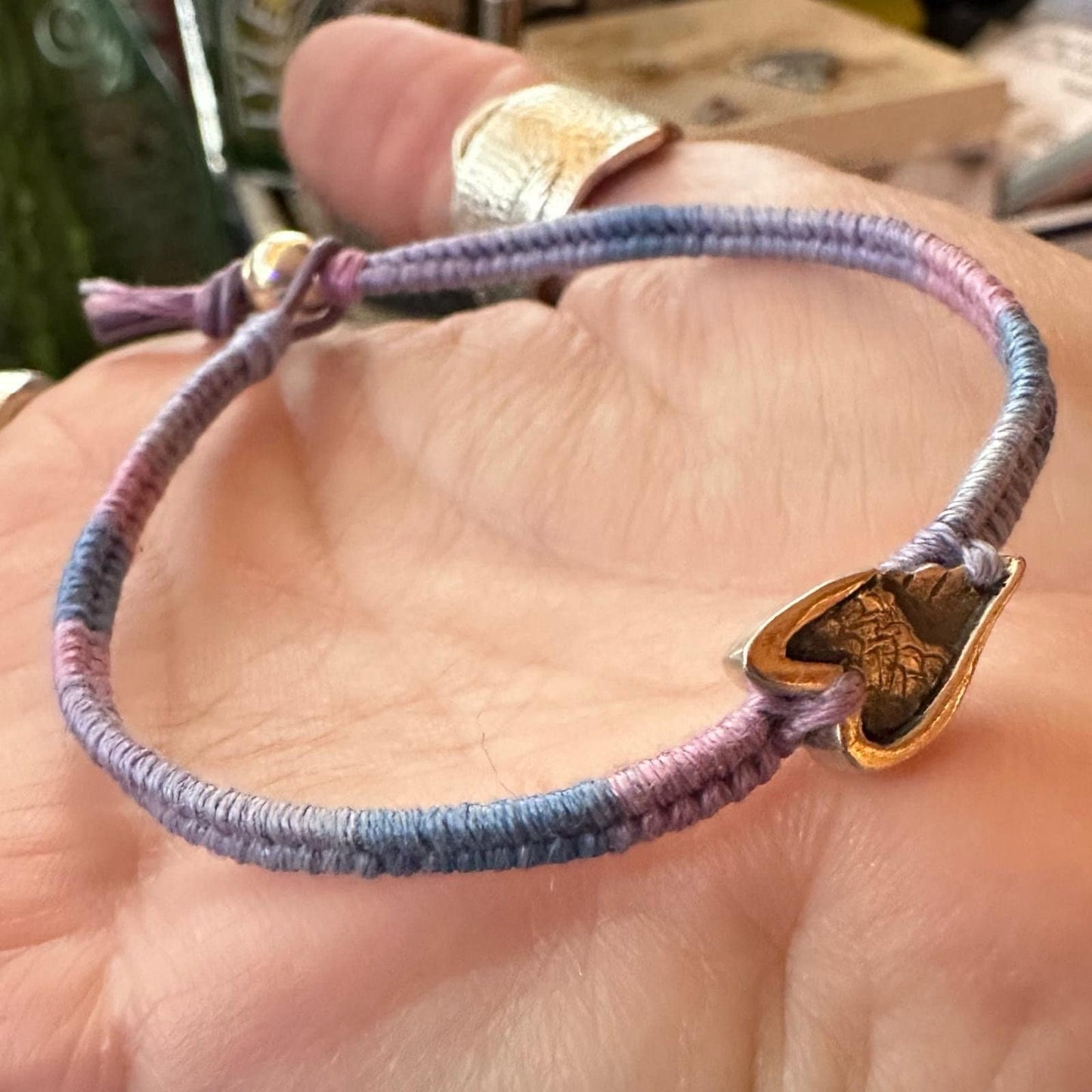 A beautiful little fine silver angel wing on a beautiful pinky purple leather, cotton and sterling silver woven charm bracelet.