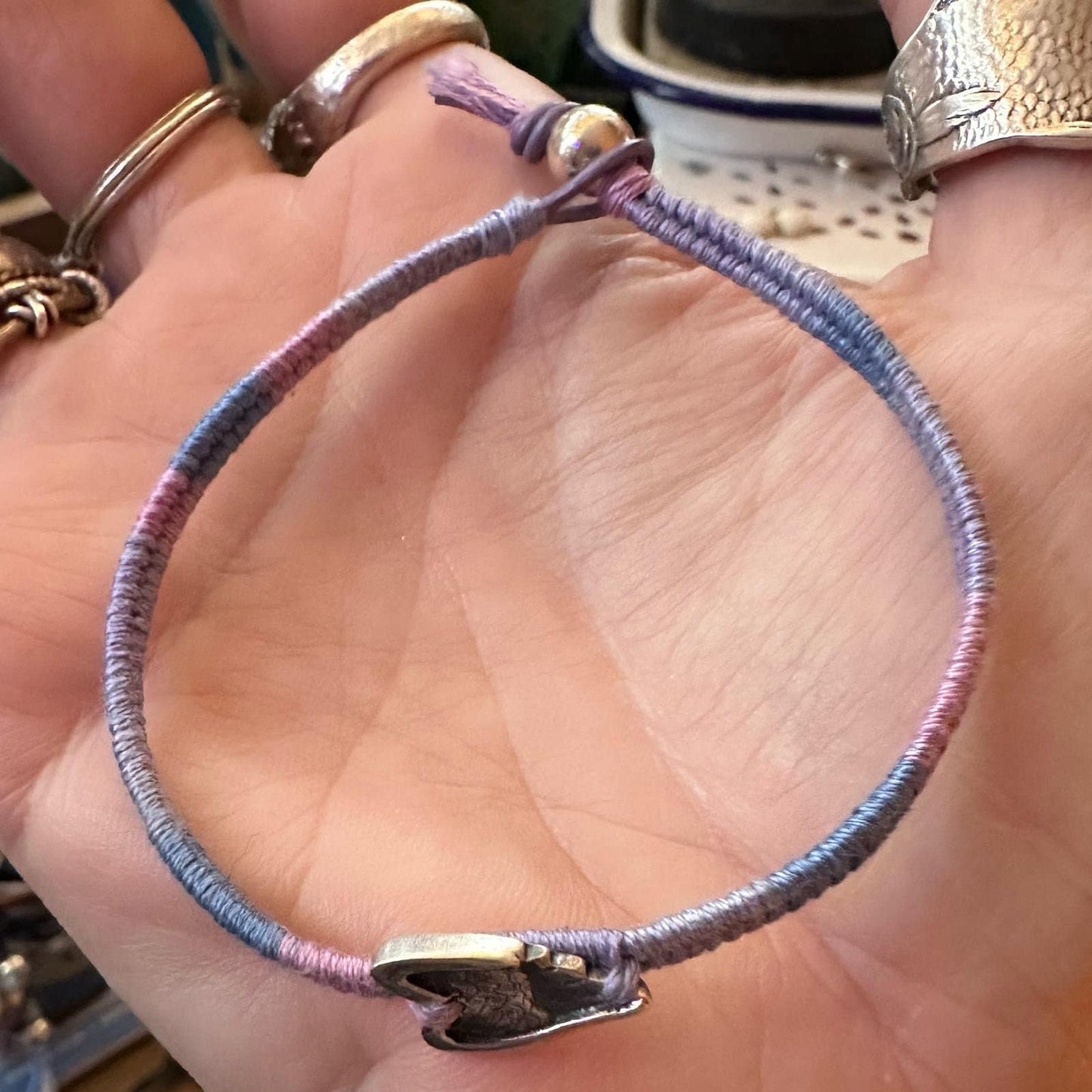 A beautiful little fine silver angel wing on a beautiful pinky purple leather, cotton and sterling silver woven charm bracelet.