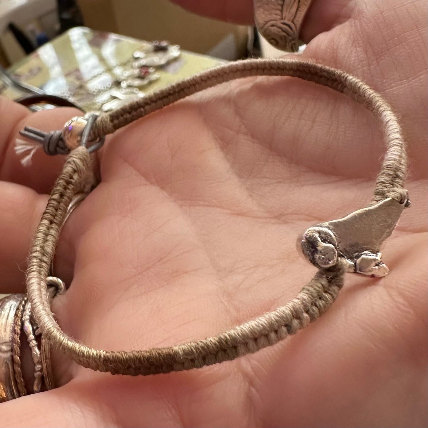 A beautiful beige leather, cotton and sterling silver friendship bracelet with a fine silver seal charm.