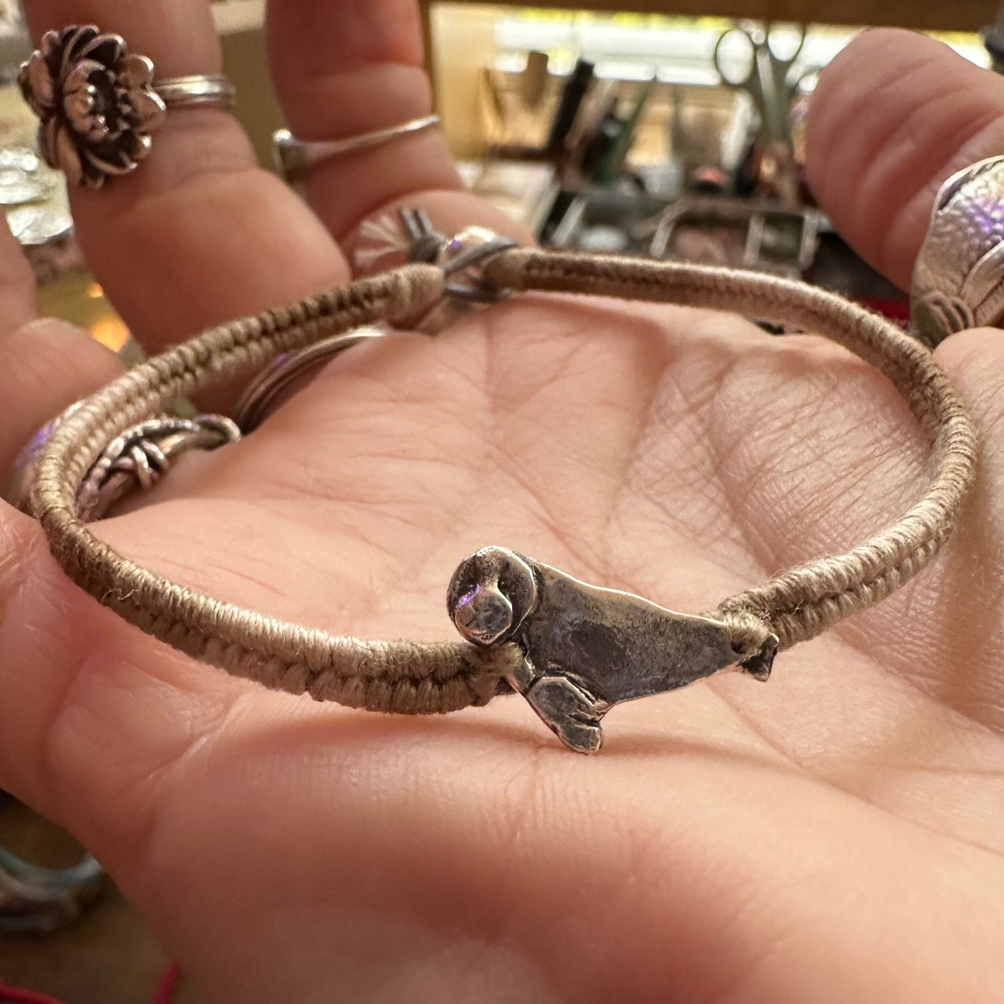 A beautiful beige leather, cotton and sterling silver friendship bracelet with a fine silver seal charm.